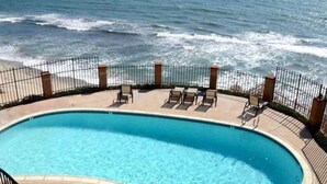 A swimming pool with a view of the ocean, surrounded by a fence and lounge chairs. - Ocean View from Living Room & porches -last min special for Nov and Dec!  (Solana Beach)