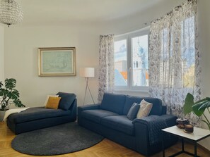A living room with a blue sofa, a round rug, a small table with a candle, and a floor lamp. - Heart of Bratislava-Blue Church views-Sleeps 5-6. (Bratislava)