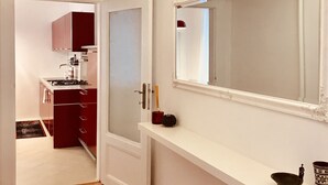 A hallway with a wooden floor, a red rug, a white console table with a mirror, and a chandelier. - Heart of Bratislava-Blue Church views-Sleeps 5-6. (Bratislava)
