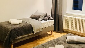 A bedroom with a bed, a radiator, a window, and a floor lamp. - Heart of Bratislava-Blue Church views-Sleeps 5-6. (Bratislava)