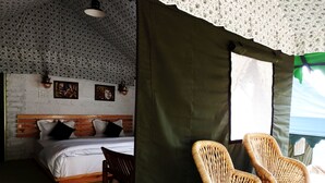 Un dormitorio con una cama de madera, dos almohadas, una mesita de noche, una silla de mimbre y una cortina verde.