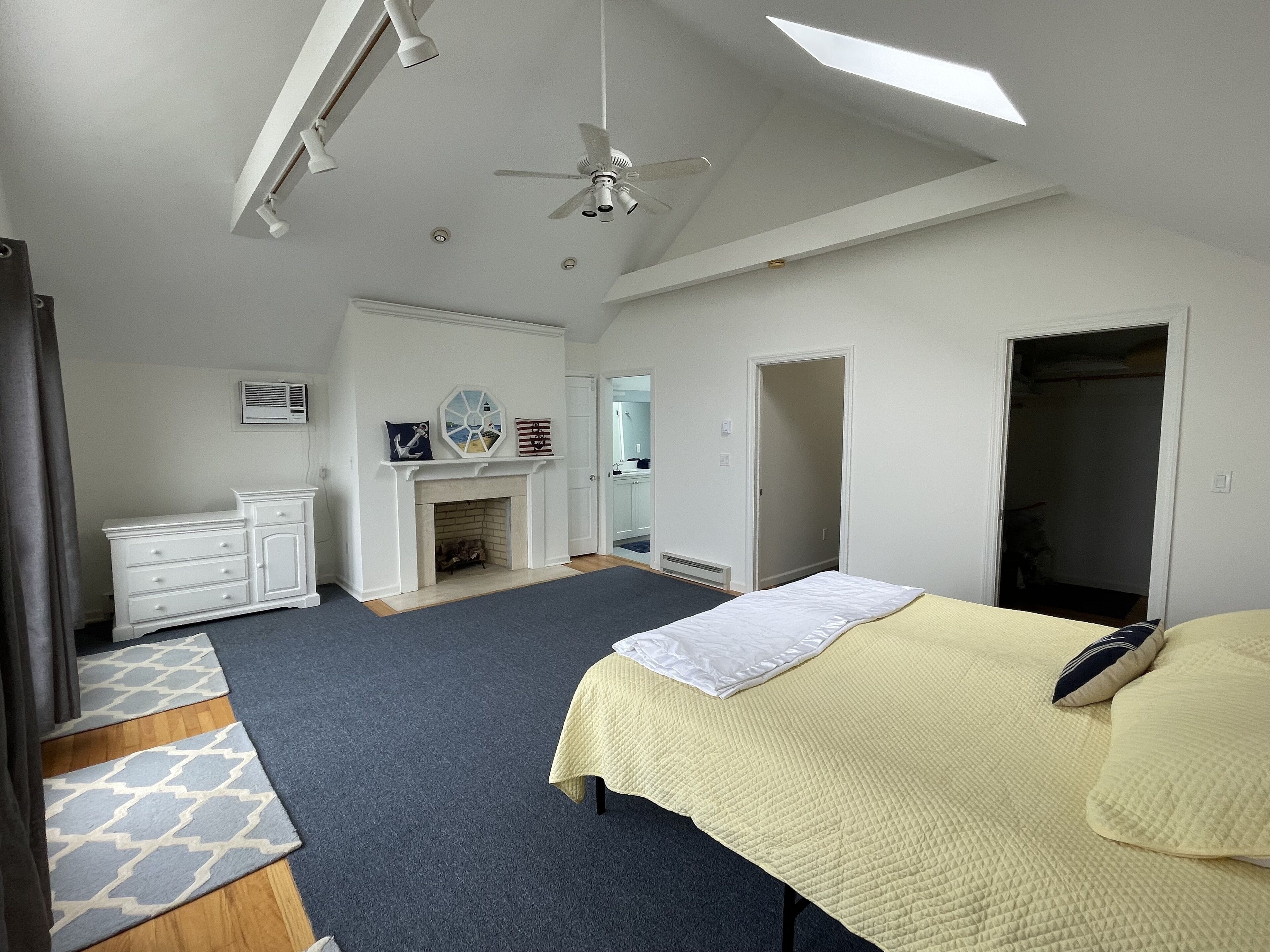 Une chambre à coucher avec un lit, une commode, une cheminée et un ventilateur de plafond.