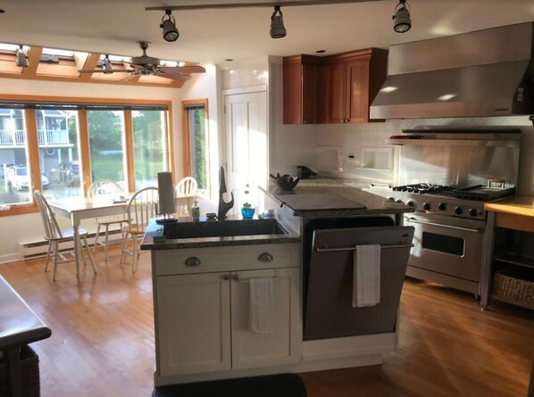 A modern kitchen with a central island, stainless steel appliances, and wooden cabinets. - Stunning direct waterfront beach house! (Fairfield)