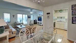 A spacious living room with a dining area, a kitchen, and a view of the outside.