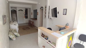 A reception area with a desk, chairs, a television, and a small plant.