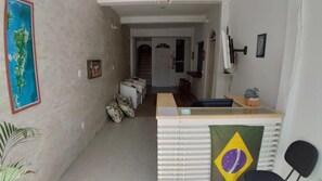 Um saguão de hotel com uma mesa de recepção, uma escadaria e um mapa na parede.