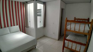 A bedroom with a bed, a bunk bed, a window with curtains, and a door.