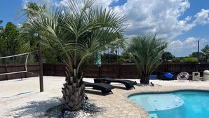 Ein Garten mit Swimmingpool, Palmen und Gartenmöbeln.