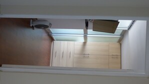 Un pasillo estrecho con ventilador de techo, tragaluz y armarios de madera.