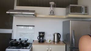 Una cocina equipada con estufa, microondas, hervidor y cafetera.