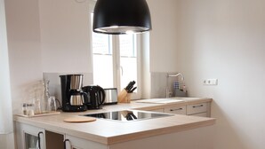 Une cuisine moderne dotée d’un îlot central, de meubles de rangement intégrés et d’un luminaire suspendu.