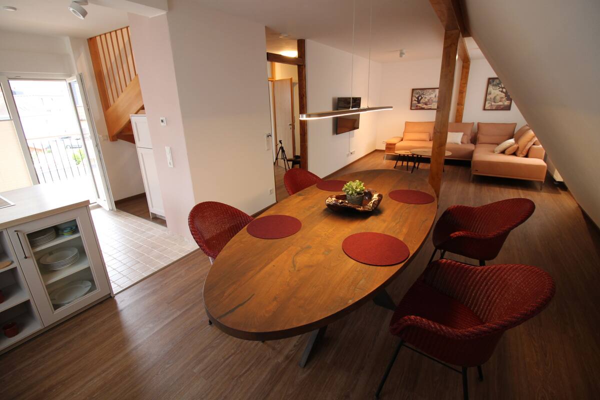 Una cocina moderna con una mesa de comedor de madera, sillas rojas y un armario empotrado.