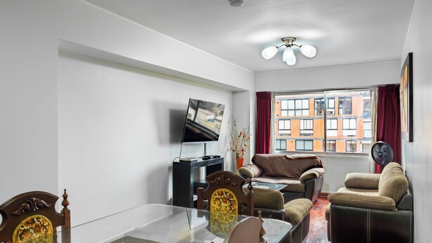 A modern living room with a glass coffee table, a sofa, a TV, and a view of a building through a window. - Great location at Miraflores  (Lima)