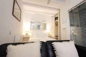 Une chambre d’hôtel comprenant un lit, des lampes de chevet, un miroir, une armoire et une porte donnant sur une salle de bain.