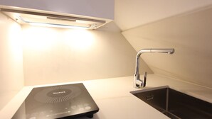 Una cocina moderna con una placa de inducción integrada, un grifo elegante y una lámpara sobre la encimera.