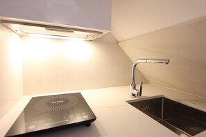 A modern kitchen with a built-in induction cooktop, a sleek faucet, and a light fixture above the countertop. - La lonja - old town Palma (Palma de Mallorca)