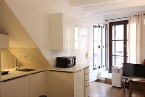 A compact kitchen with a microwave, sink, and cabinets. - La lonja - old town Palma (Palma de Mallorca)