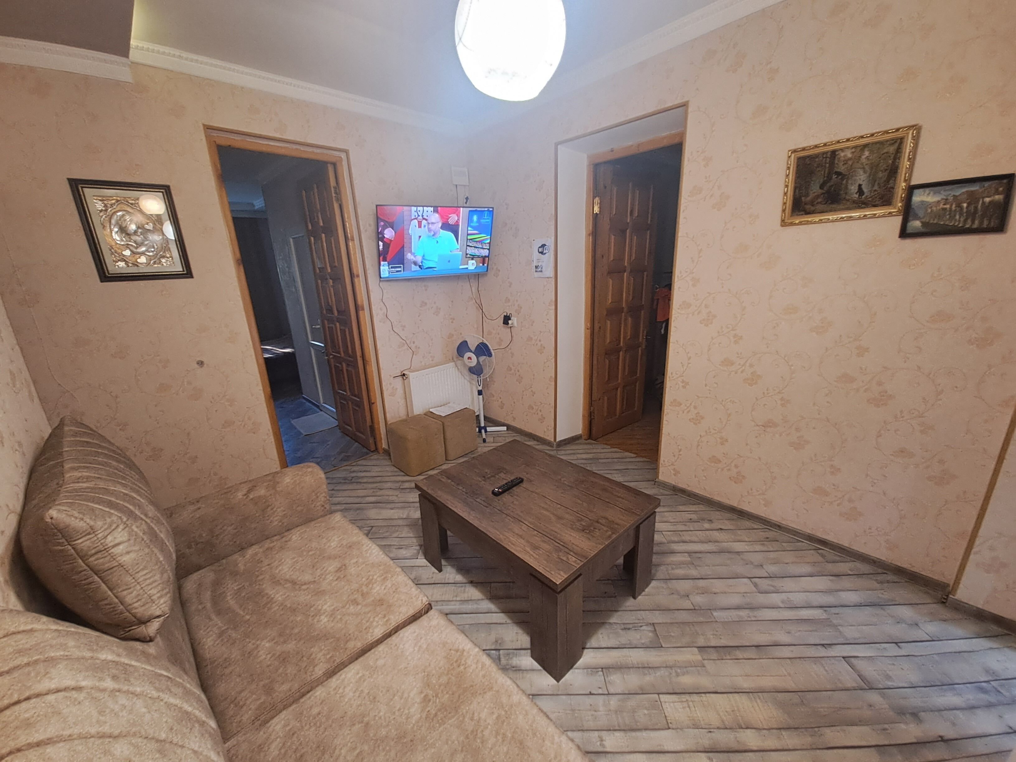 Una sala de estar con una mesa de centro de madera, un sofá y un televisor montado en la pared.