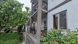 A residential building with a stone-tiled entrance, a balcony with potted plants, and a staircase leading to the upper floors. - Guest House Akhaltsikhe (Akhaltsikhe)