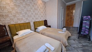 A hotel room with two beds, a wooden wardrobe, a mirror, and a patterned wall. - Guest House Akhaltsikhe (Akhaltsikhe)