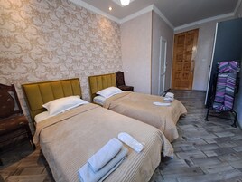 A hotel room with two beds, a wooden wardrobe, a mirror, and a patterned wall.