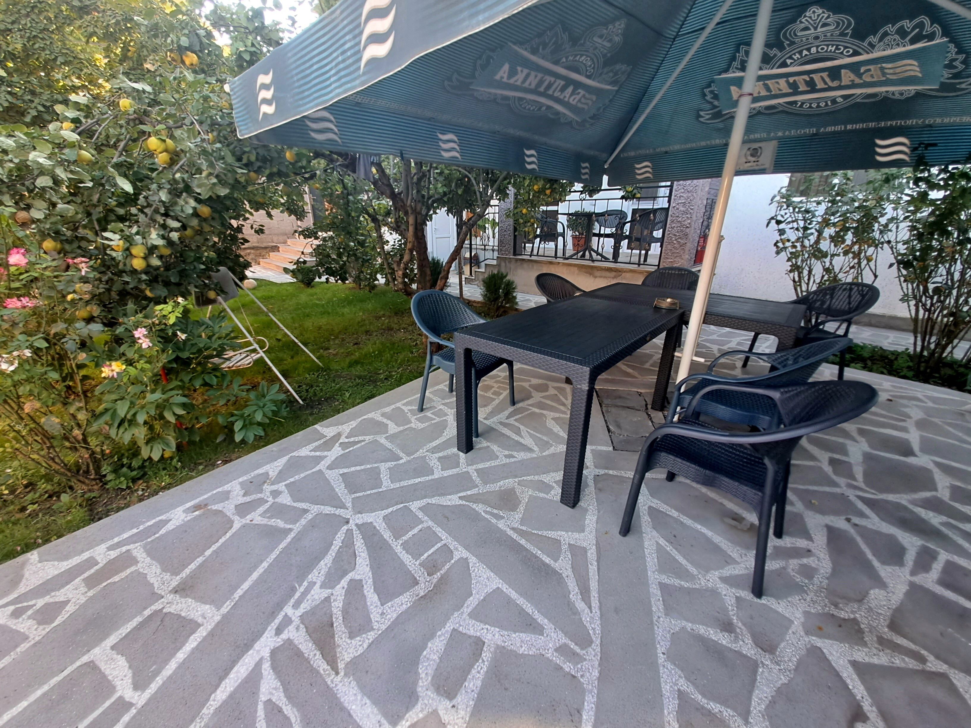 Un espacio al aire libre con patio, una mesa, sillas, suelo de piedra con diseño y un gran paraguas.
