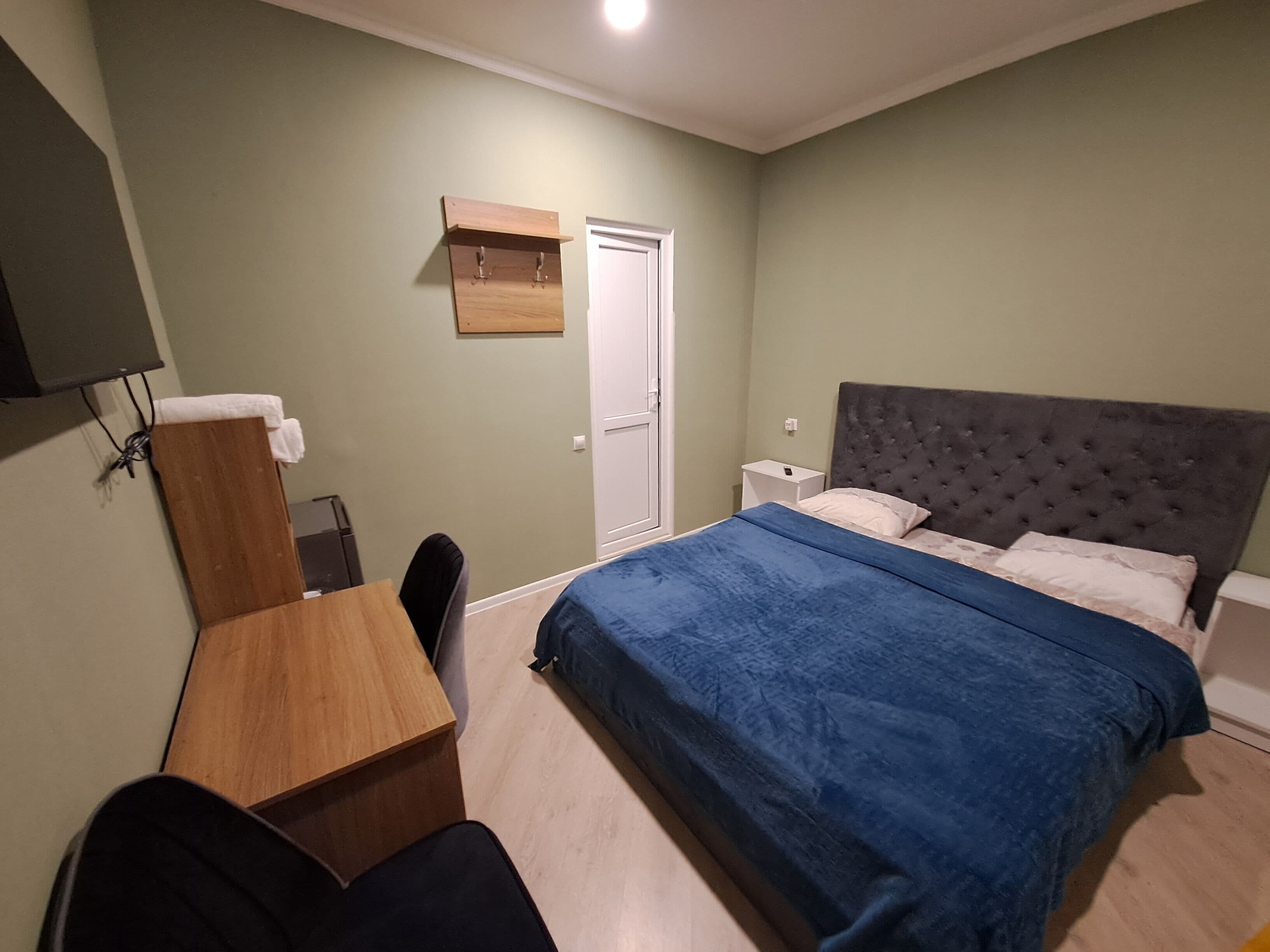 Quarto com cama, escrivaninha, cadeira, guarda-roupa e porta.