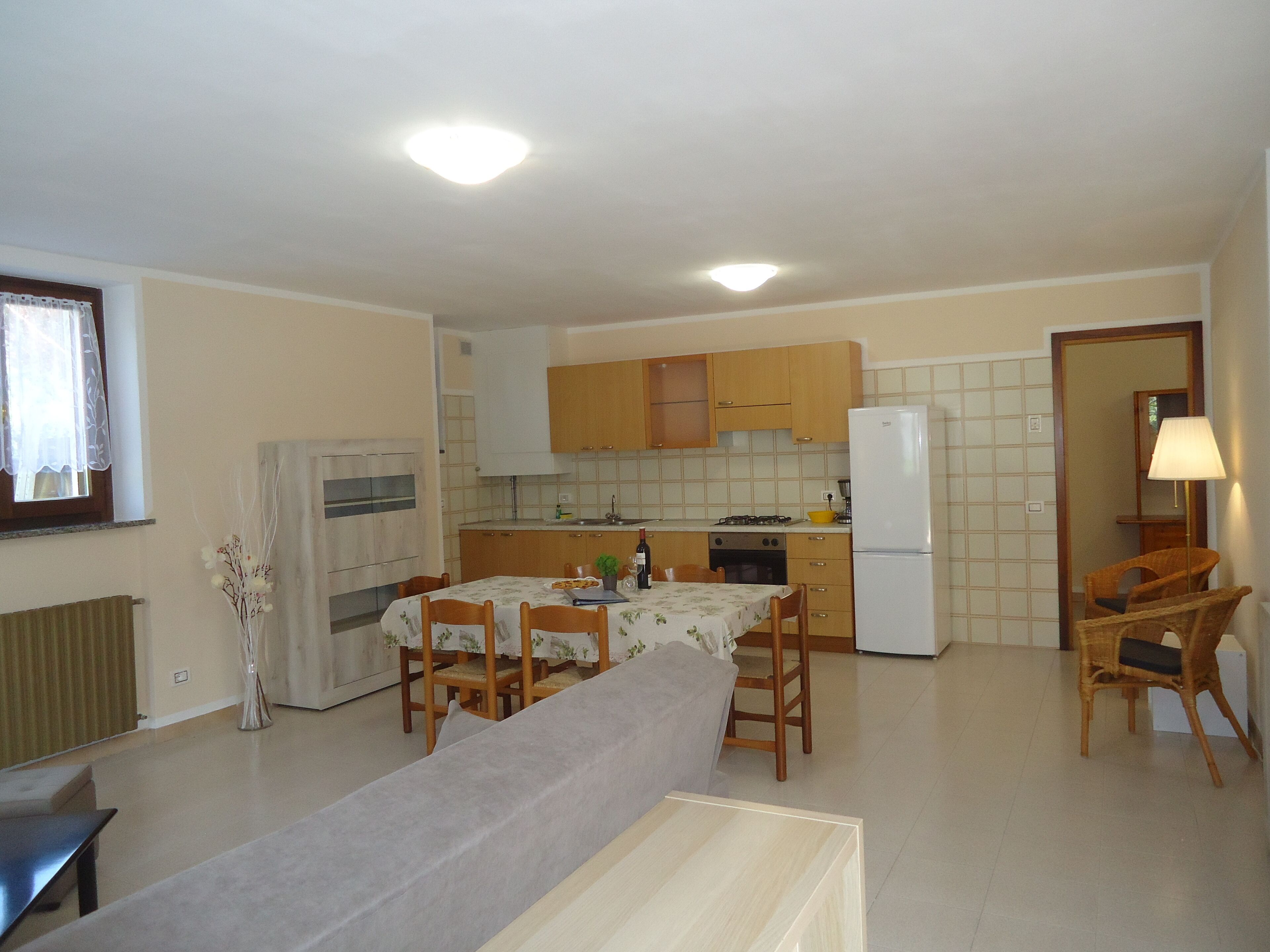 A compact kitchen with wooden cabinets, a dining area with a table and chairs, and a refrigerator.