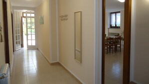 A hallway with a radiator, a door leading to a dining area, and a mirror on the wall. - Ground floor apartment up to 6 pers., 3 bedrooms, terrace and garden, 300m to the lake (Crone)
