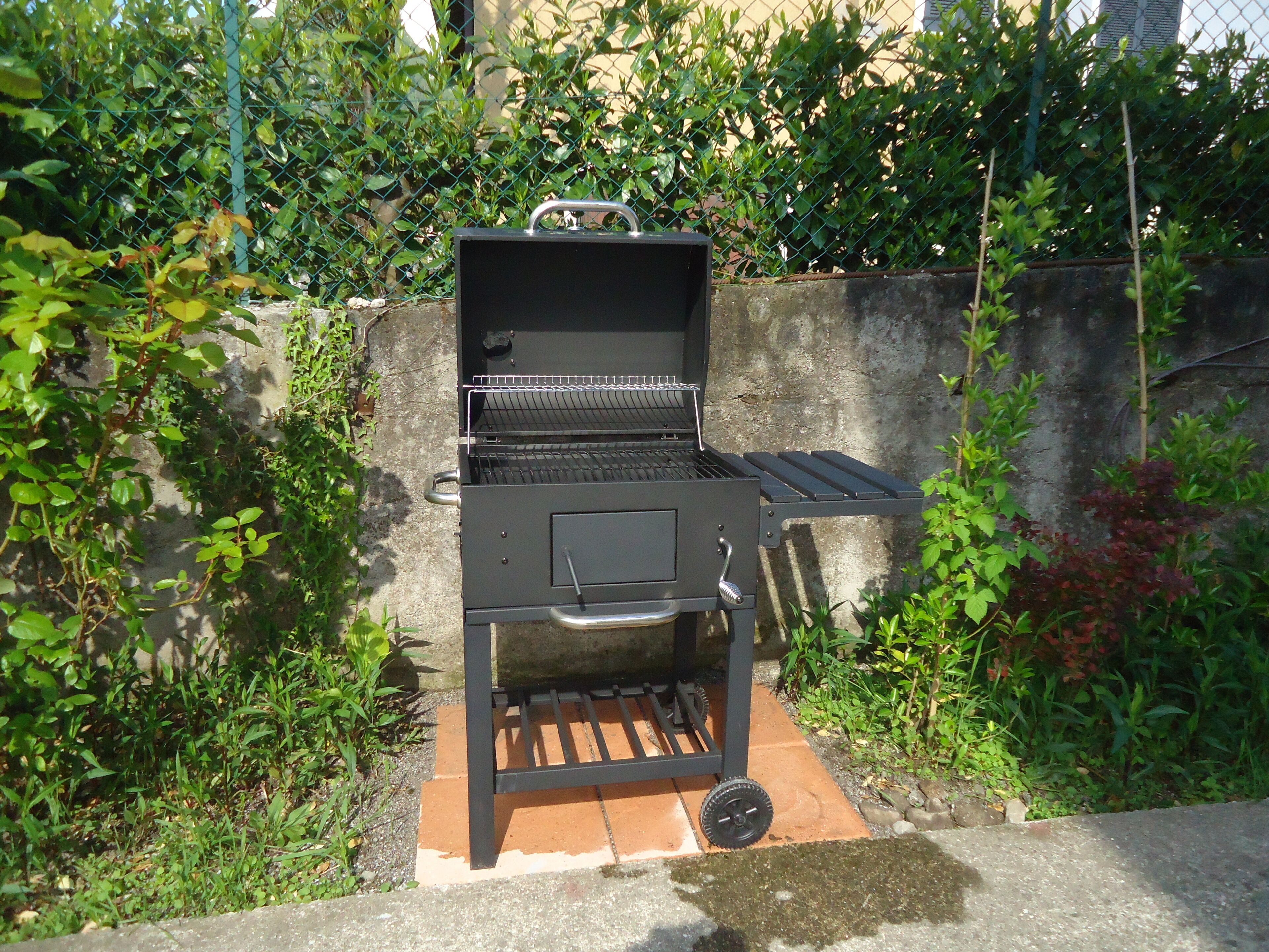 An outdoor grill with a metal grate, a handle, and a wheel for mobility.
