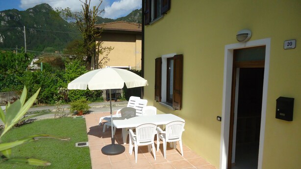 A patio with a table and chairs, an umbrella, and a door marked with the number 20. - Ground floor apartment up to 6 pers., 3 bedrooms, terrace and garden, 300m to the lake (Crone)