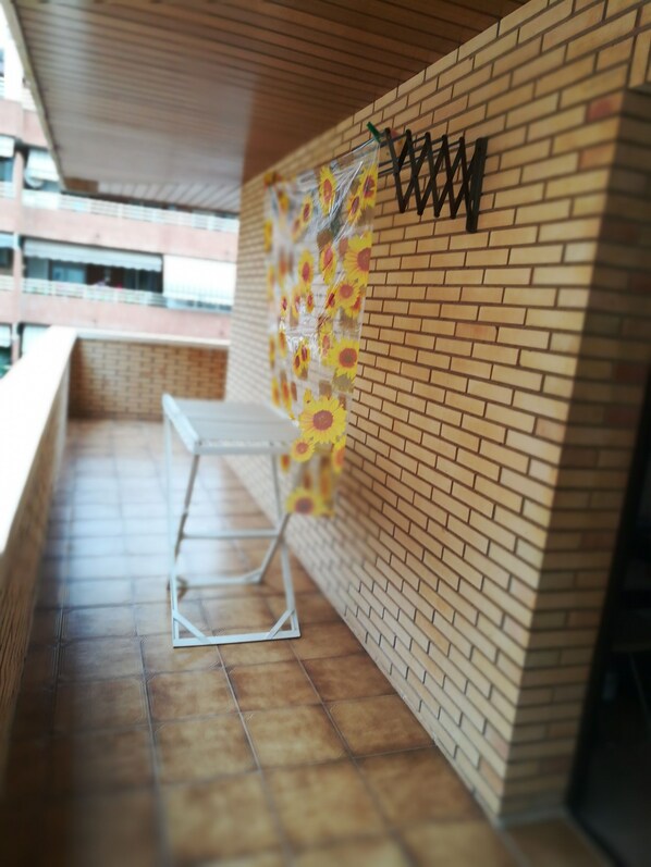 A covered outdoor area with a brick wall, a metal railing, and a table.