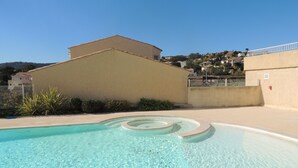 Una piscina limpia de diseño sencillo, rodeada por un muro bajo y una cerca.