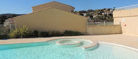 A clear swimming pool with a simple design, surrounded by a low wall and a fence.