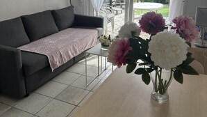 Una sala de estar con un sofá, una mesita de centro y un florero con flores.