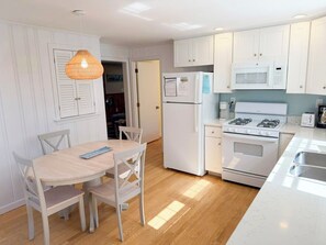 A compact kitchen with white cabinetry, a built-in microwave, a stove, and a refrigerator.