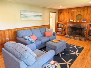 A living room with a sectional sofa, a fireplace, and a bookshelf. - Cozy three bedroom home with updated eat in kitchen (Dennis Port)