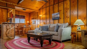 Een gezellig cabin interieur met houten details, een bank, een bijzettafeltje en een eethoek.