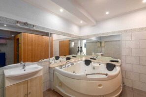 A modern bathroom with a large bathtub, a sink, and a mirror.
