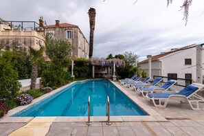 A swimming pool with lounge chairs and a pergola.