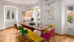 Un coin repas avec une table en bois, des chaises colorées et un luminaire suspendu au design moderne.