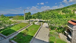 A residential area with a paved pathway, green lawns, and trees.