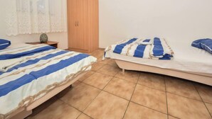 Een kamer met twee bedden, een houten garderobe en een klein tafeltje met een decoratief object.