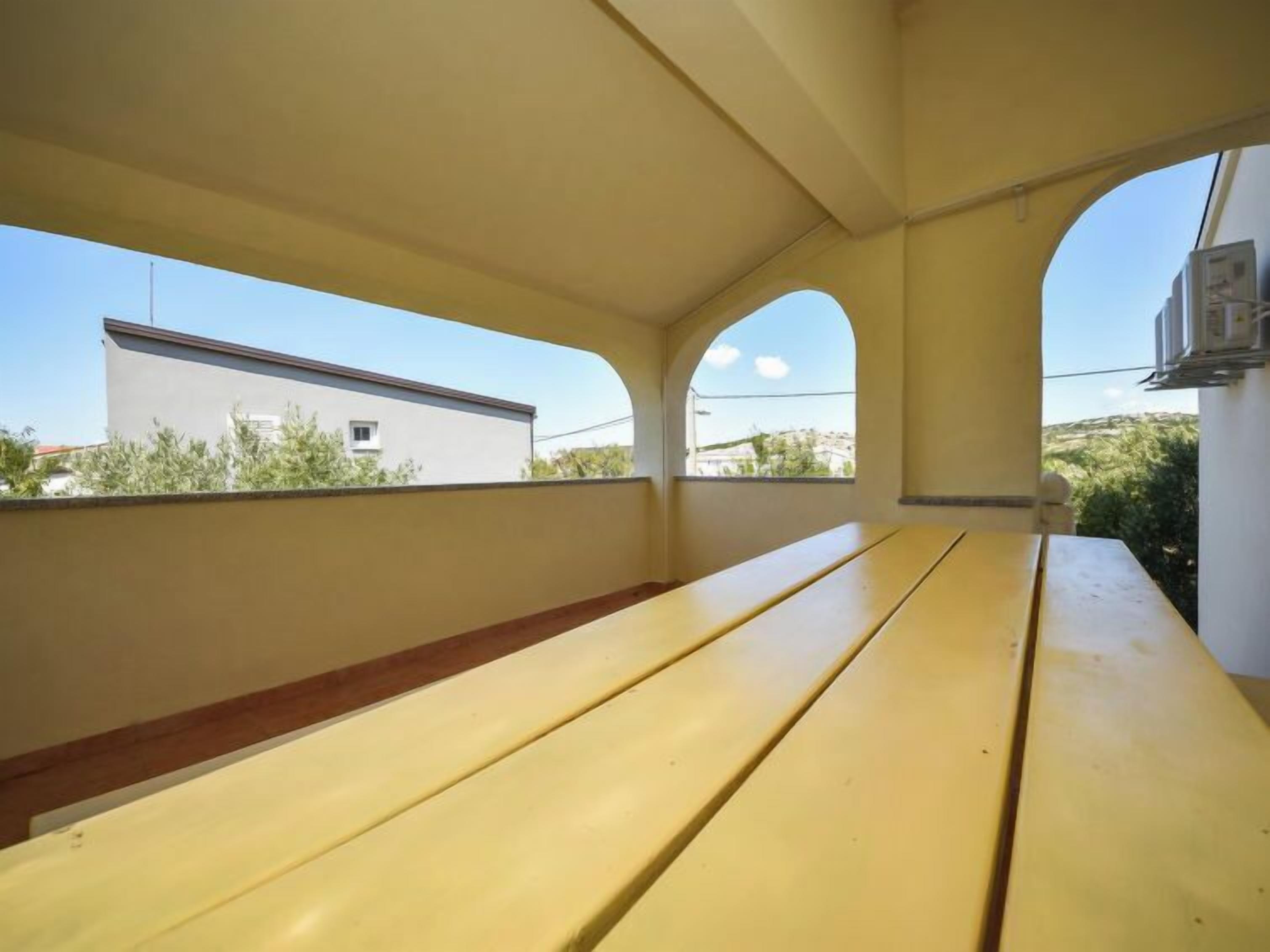A room with a long, yellow wooden bench and a large window.