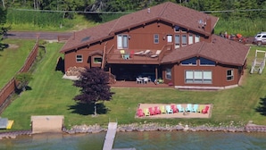 A large two-story house with a deck, a swimming pool, and a dock.