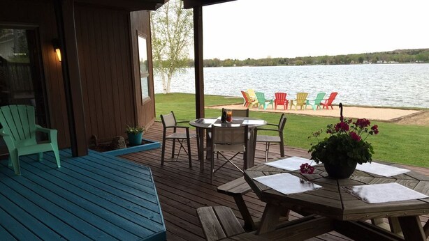 A wooden deck with outdoor seating and a view of a lake.