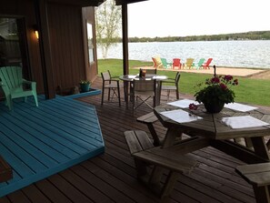 Une terrasse en bois avec des sièges extérieurs et une vue sur un lac.