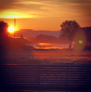 A sunset over a rural landscape with a bench in the foreground. - Eco Camp Norway - Hostel (Smøla)