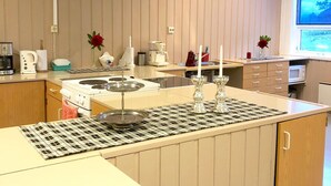 A kitchen with a stove, sink, and a window. - Eco Camp Norway - Hostel (Smøla)