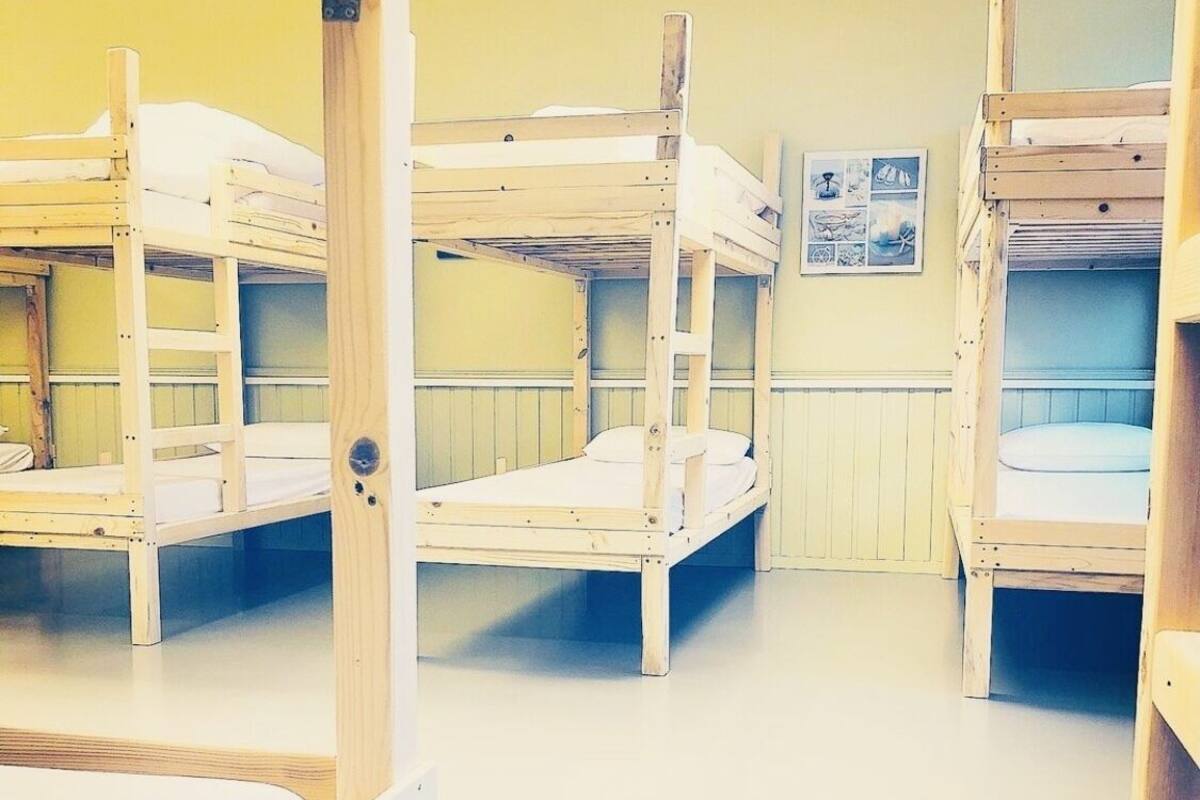 A room with bunk beds and a bulletin board on the wall.
